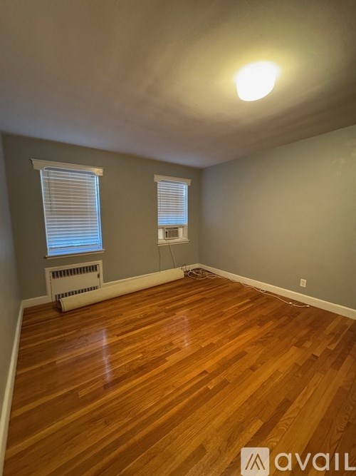 A room with wooden floors and a window with blinds.