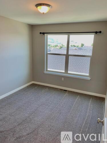 A room with a carpeted floor and a window with blinds.