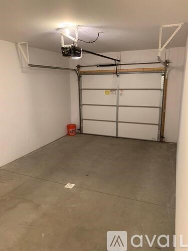 A garage with a white door and a red container on the floor.