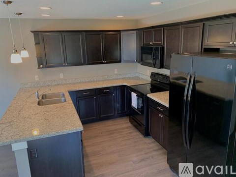 A kitchen with dark brown cabinets and a granite countertop.