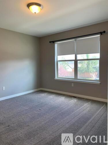 A room with a carpeted floor and a window with blinds.