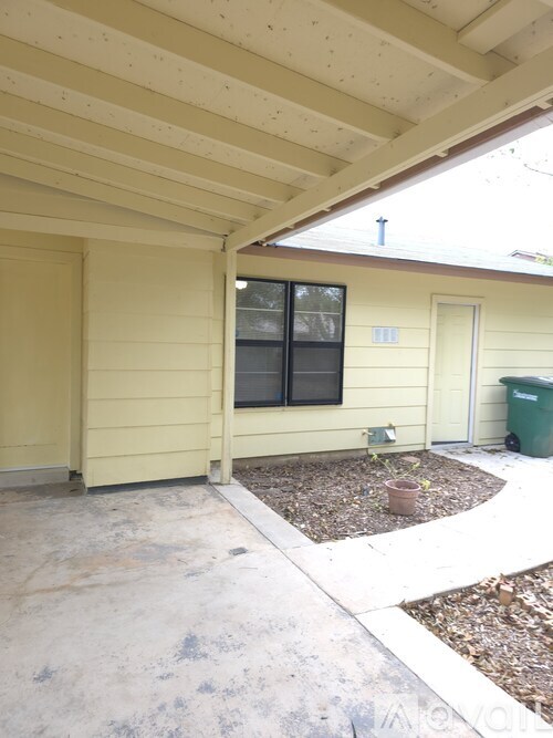 A small tree in a pot sits on a concrete patio.