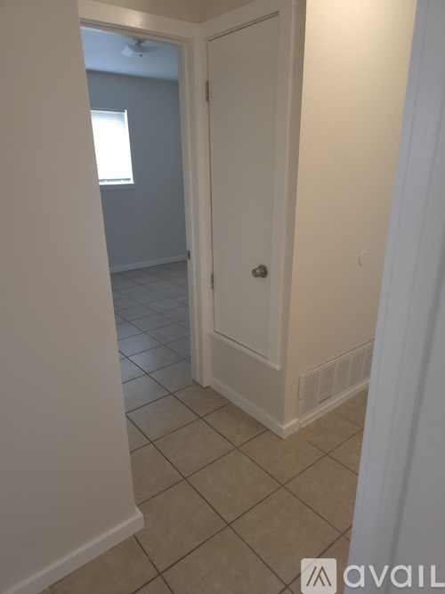 A hallway with a white door and tiled floor.