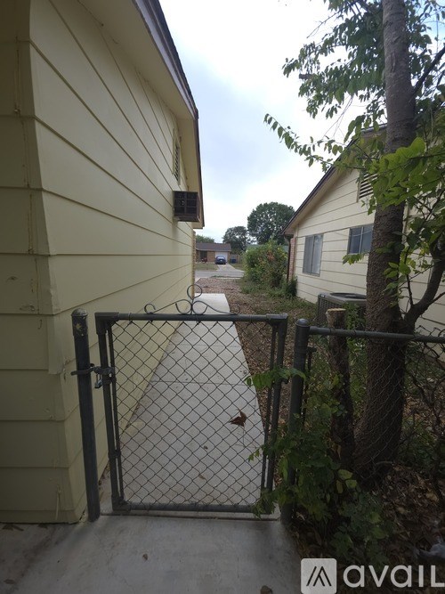 A chain link fence with a gate is in front of a house.