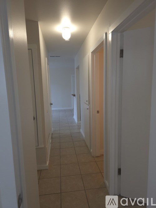 A long hallway with white walls and tiled floors.