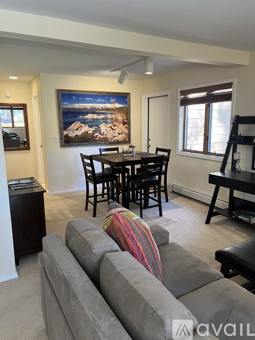 A living room with a grey couch and a painting on the wall.
