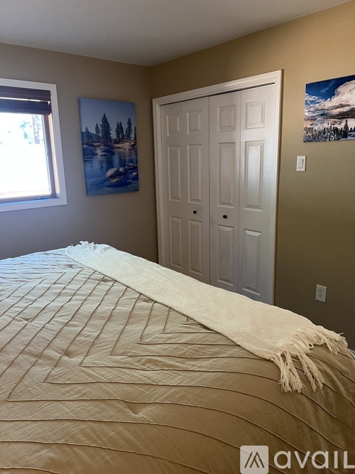 A bedroom with a large bed and two pictures on the wall.