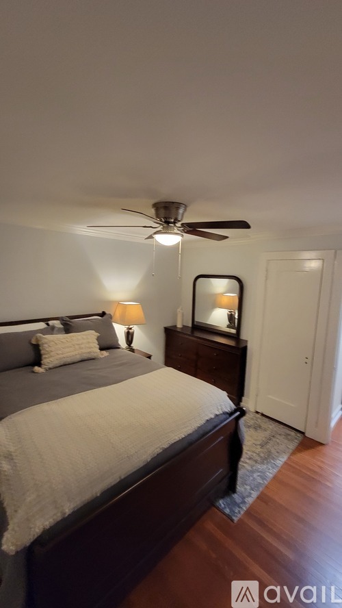 A bedroom with a bed, a ceiling fan, and a nightstand with a lamp.