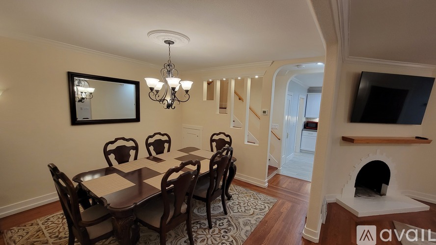 A dining room with a table set for six and a chandelier hanging from the ceiling.