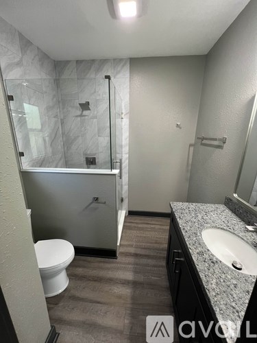 A bathroom with a marble shower and a white toilet.