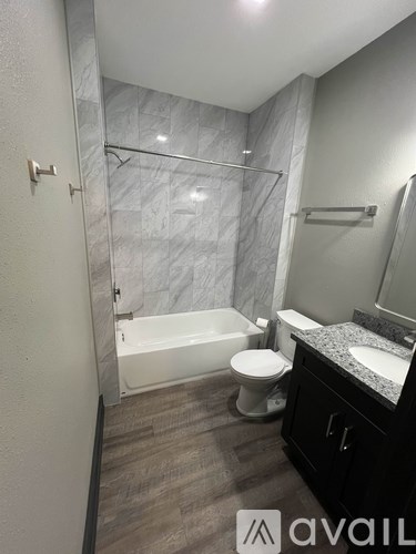 A bathroom with a marble shower, toilet, and sink.