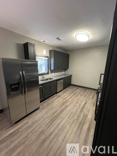 A kitchen with a refrigerator, sink, and cabinets.