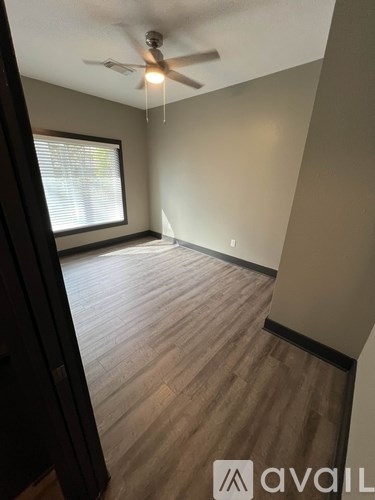 A room with a ceiling fan and wooden flooring.