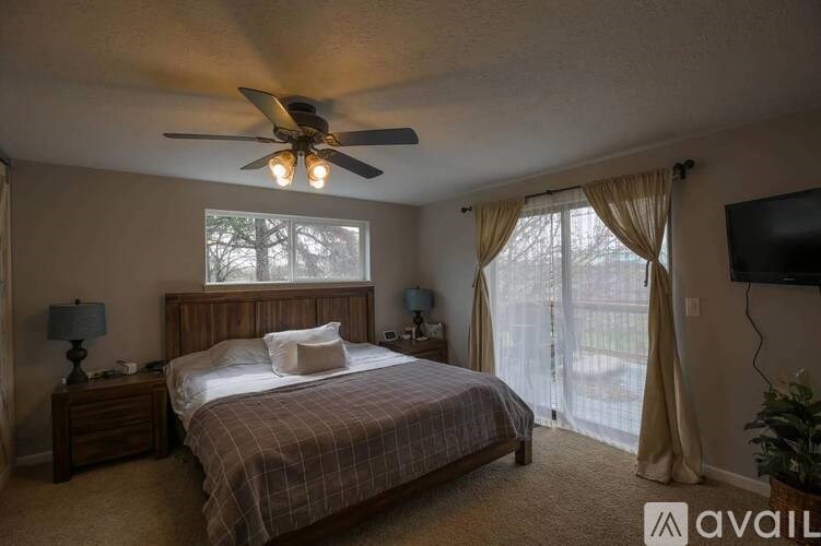 A bedroom with a bed, nightstand, and a ceiling fan.