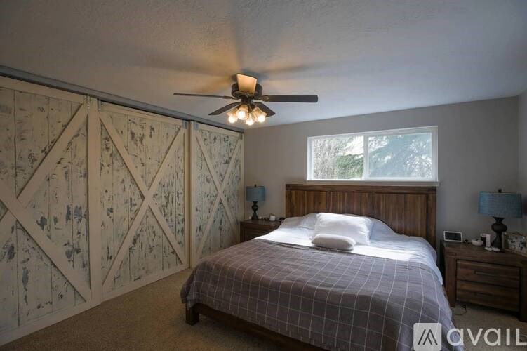 A bedroom with a bed, a ceiling fan, and a wall with a floral pattern.