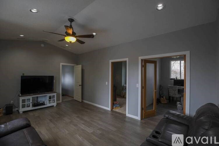 A living room with a ceiling fan and a television.