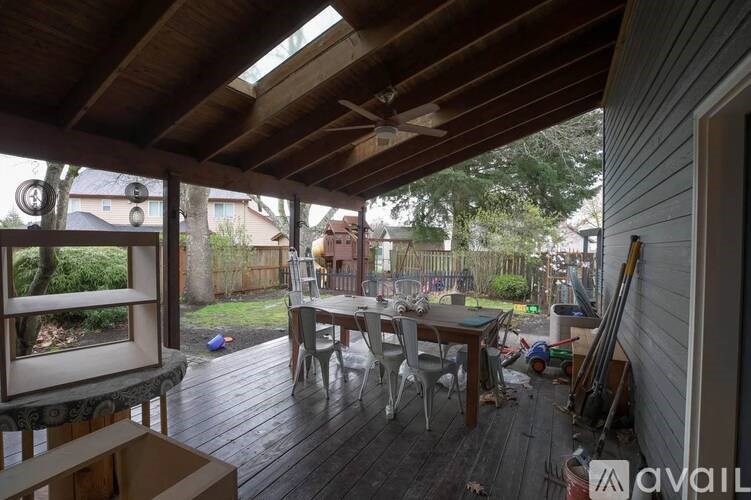 A wooden deck with a table and chairs is under a wooden roof.