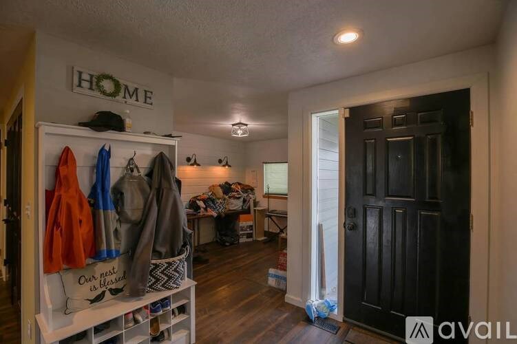 A room with a black door and a white wall with the word HOME on it.