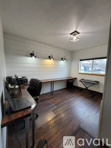 A room with a desk and chairs with a laptop on it.