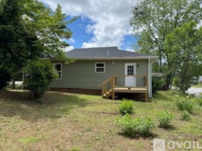 A house with a grey roof and a porch surrounded by greenery.
