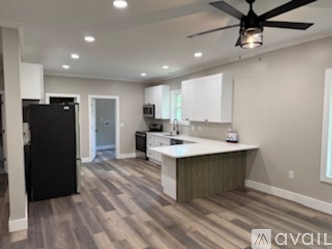 A kitchen with a black refrigerator and a ceiling fan.
