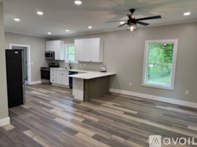 A kitchen with a black refrigerator and white cabinets.