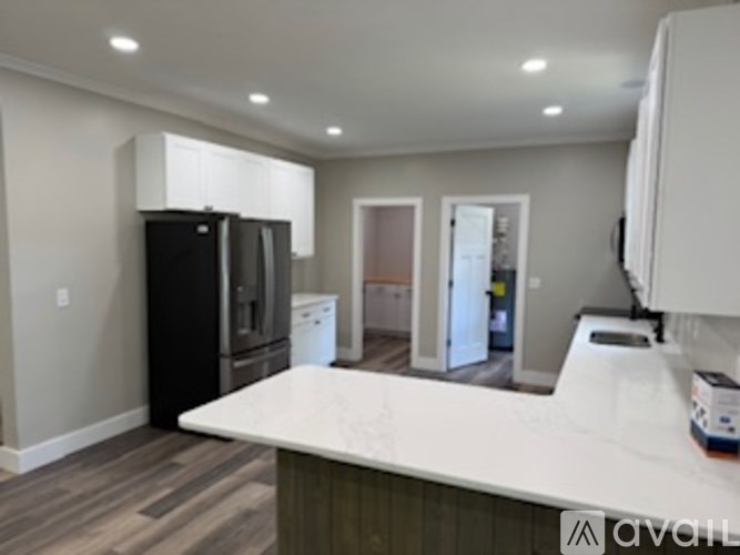 A kitchen with a black refrigerator and white countertops.