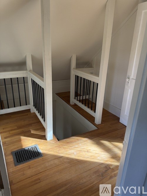 A wooden staircase with a metal grate on the floor.