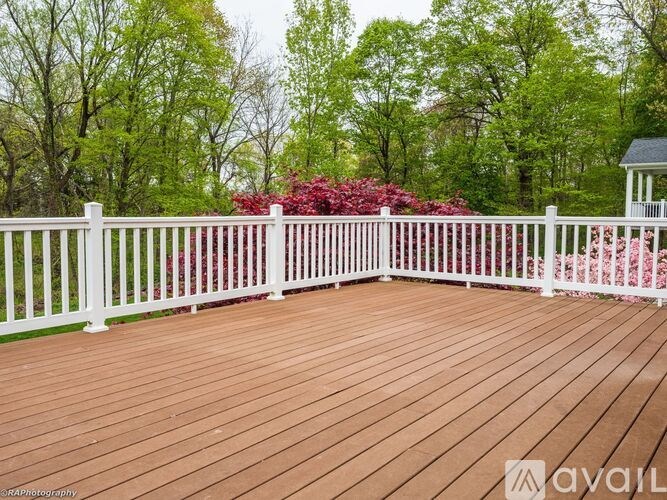 A wooden deck with a white railing and a gazebo in the background.