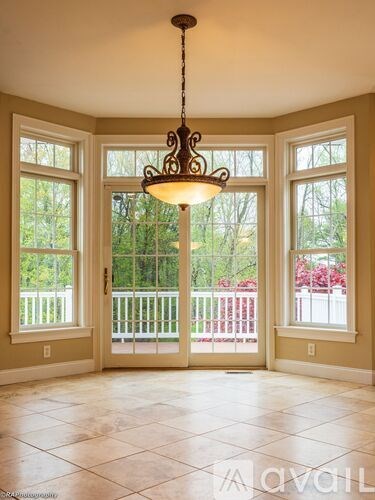 A chandelier hangs in a room with a view of a deck.
