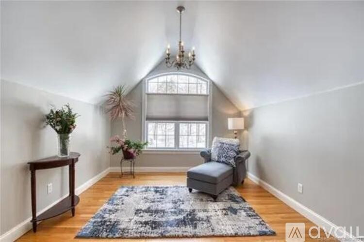 A living room with a grey couch, a wooden table, a blue rug, and a chandelier.