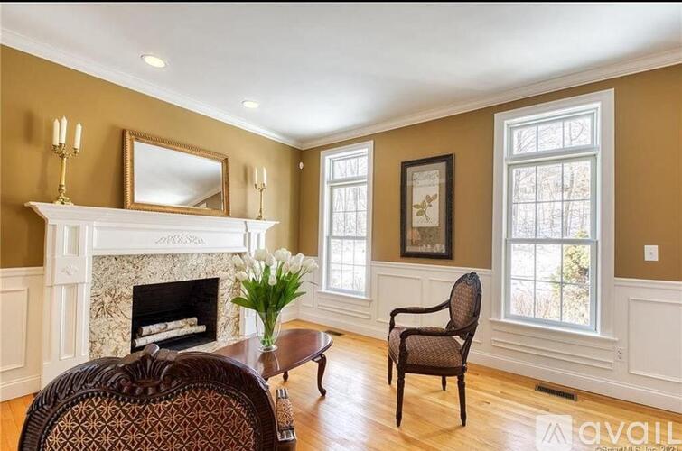 A living room with a fireplace, a chair, and a vase of flowers.