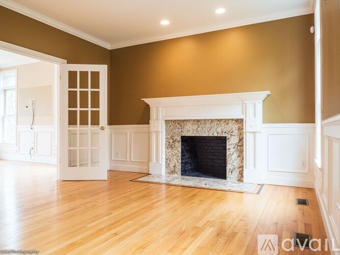 A large, empty room with a fireplace and wooden floors.