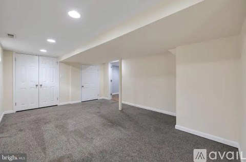 A spacious room with white walls and a carpeted floor.
