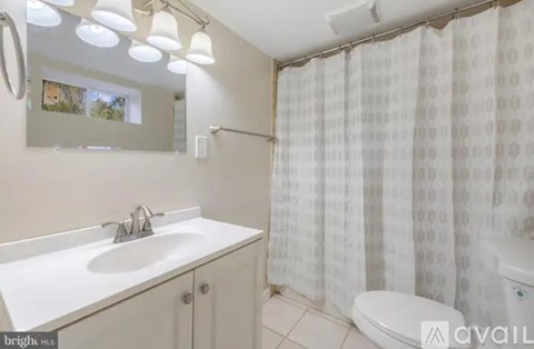 A white sink and toilet in a bathroom with a shower curtain.