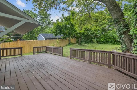 A wooden deck with a railing and trees in the background.