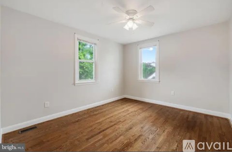 A room with wooden floors and two windows.
