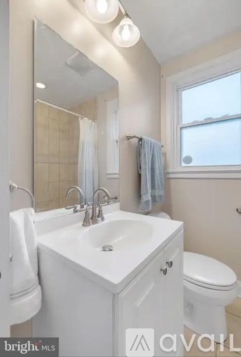 A white bathroom with a sink, toilet, and mirror.