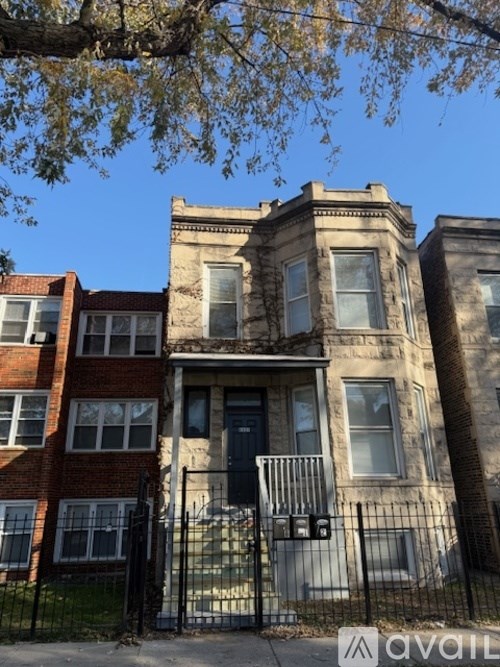 A row of three houses with a black iron fence in front.