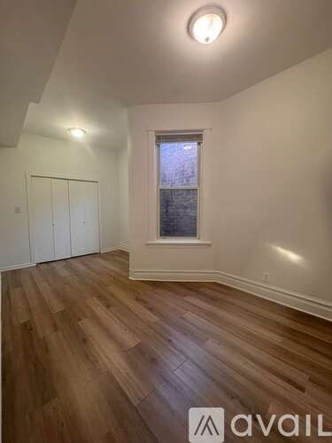 A room with wooden floors and a window with a view of a building.