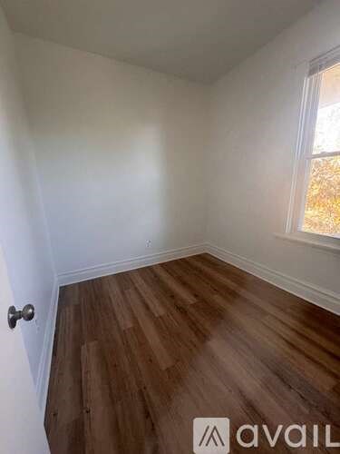 A room with wooden flooring and a window letting in light.