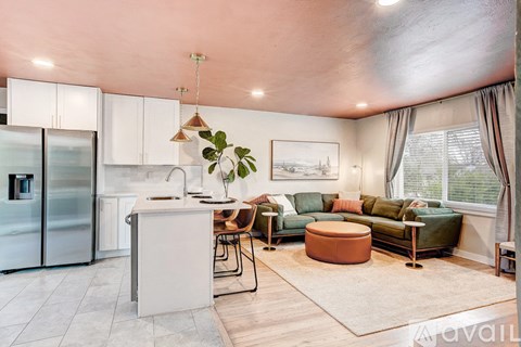 A modern kitchen with a refrigerator, a dining table with chairs, and a sofa with a cushion.