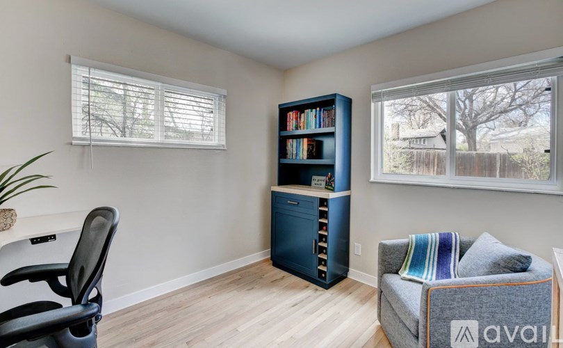 A room with a blue bookshelf, a black chair, and a grey couch.