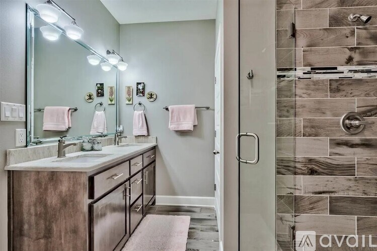 A bathroom with a vanity, mirror, and a walk-in shower.