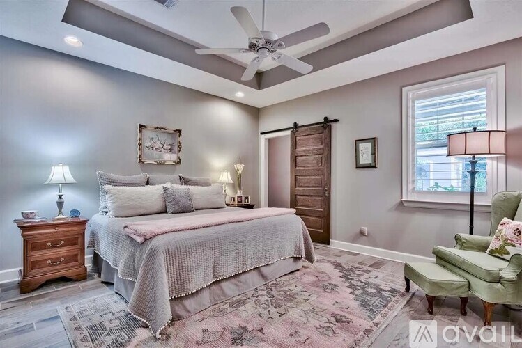 A bedroom with a bed, a chair, and a ceiling fan.