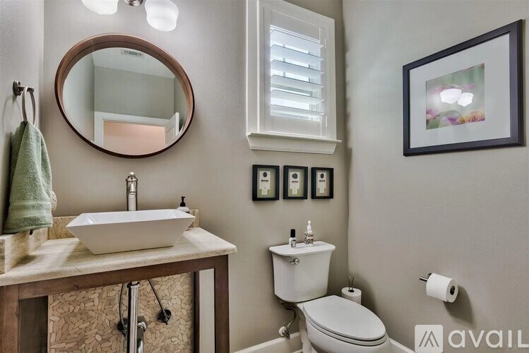 A bathroom with a toilet, sink, mirror, and towel rack.