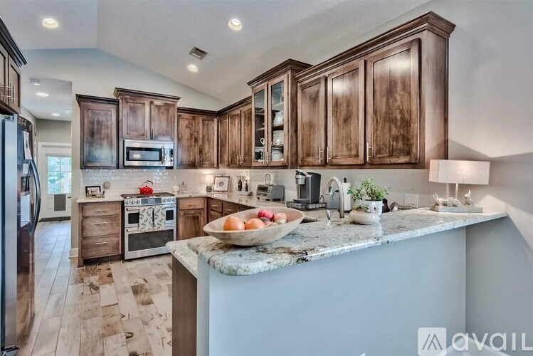 A kitchen with wooden cabinets and a marble island.