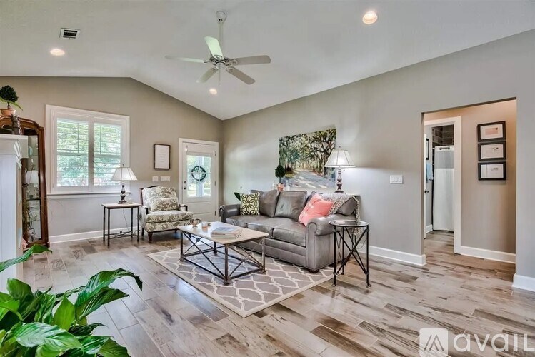 A living room with a grey couch and a rug.