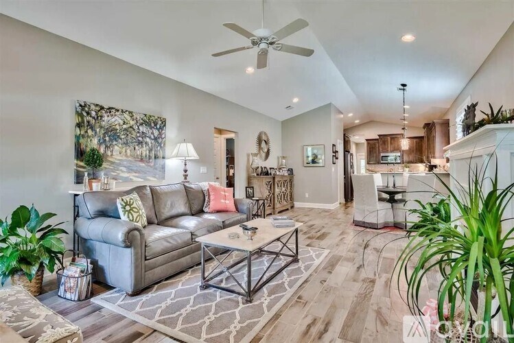 A living room with a grey couch and a painting on the wall.
