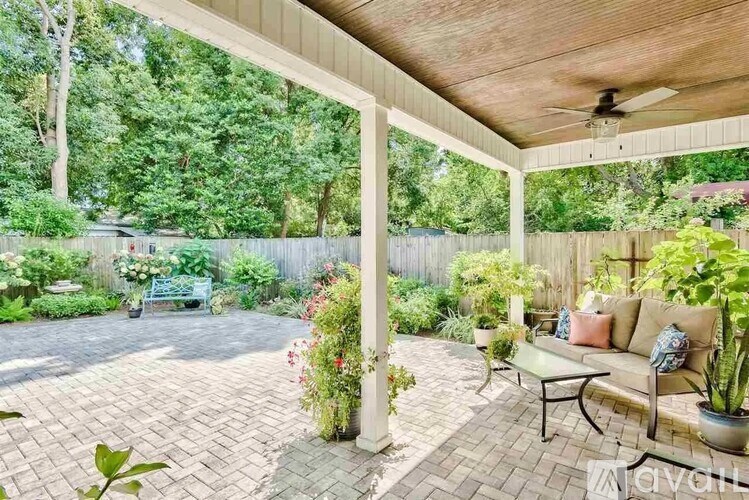 A patio with a couch, pillows, and plants.